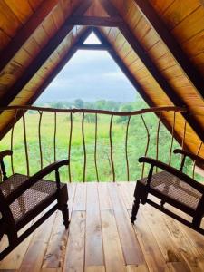 シギリヤにあるPrana Ayurveda Chalet- Sigiriyaの木製デッキ(野原の景色を望むベンチ2台付)