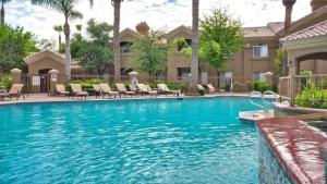 een zwembad met stoelen en een huis bij Cozy 1-Bdrm Scottsdale Condo next to pool in Scottsdale