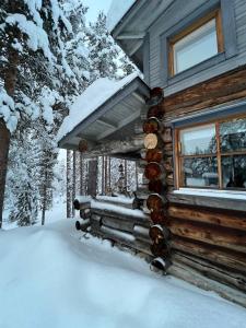 uma cabana de madeira com neve ao lado em Rauhallinen kelohuoneisto lähellä palveluita, Peacefull Log apartment at Ylläs em Ylläsjärvi