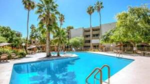 a large swimming pool with palm trees and a building at Charming 2Bd-2Bth in Heart of Old Town Scottsdale in Scottsdale