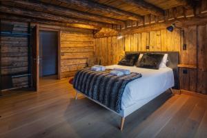 a bedroom with a bed in a log cabin at Chalet Melussac - OVO Network in Le Grand-Bornand