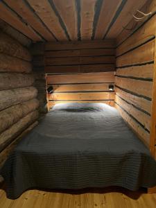 Ce lit se trouve dans un dortoir doté de murs et de plafonds en bois. dans l'établissement Rauhallinen kelohuoneisto lähellä palveluita, Peacefull Log apartment at Ylläs, à Ylläsjärvi
