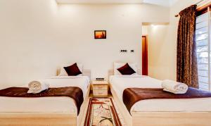 twee bedden in een kamer met witte muren bij royal stay in Madurai