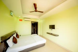een slaapkamer met een wit bed en een plafondventilator bij Goroomgo Deep Ganga Inn Near Sea Beach Puri in Puri
