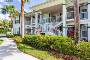 un bâtiment avec des palmiers et des fleurs devant lui dans l'établissement Positano Vacation Rental, à Lely Resort