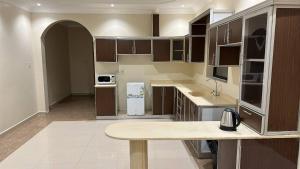 a large kitchen with a table in the middle of it at فلور الخليجية للشقق المخدومة Flowersuite1 in Dammam +43 photos
