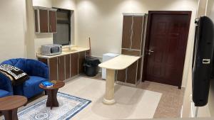 a living room with a blue couch and a table and a door at فلور الخليجية للشقق المخدومة Flowersuite1 in Dammam