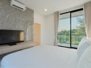 a bedroom with a large bed and a tv at บ้านพูลวิลล่าหนองคาย Lyntana in Nong Khai