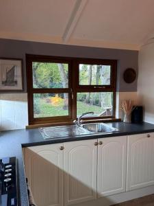 a kitchen with a sink and two windows at Woodside Lodge, Weybourne, Holt in Weybourne