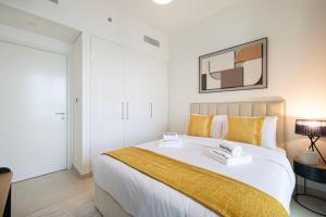 una camera da letto con un grande letto bianco con cuscini gialli di SmartStay at Downtown Views - Best Burj Khalifa View - Brand New Luxury Apartments a Dubai