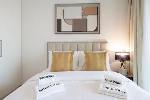 una camera da letto con un letto bianco con due cuscini sopra di SmartStay at Downtown Views - Best Burj Khalifa View - Brand New Luxury Apartments a Dubai