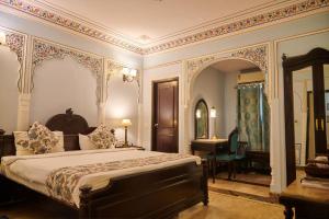 a bedroom with a large bed and a desk at WelcomHeritage Traditional Haveli in Jaipur