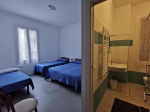 Habitación con 2 camas y baño con lavabo. en Affittacamere Montecarlo, en Laigueglia