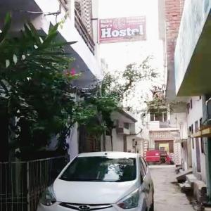 a white car parked on a street next to a building at Baba Boys Hostel and Baba Trailer Truck Transport in Lucknow