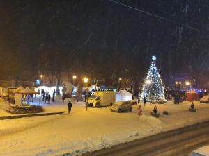 a christmas tree in a parking lot in the snow at Apartamentai Harmonija in Akmenė