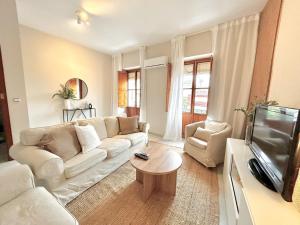 a living room with a white couch and a tv at La Casa de Carmen in Castilleja de la Cuesta