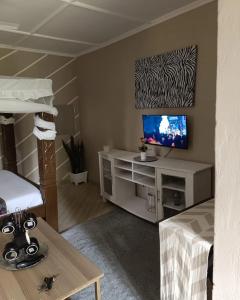 a living room with a television and a bed at LOFTY DIANI STUDIO'S in Kwale