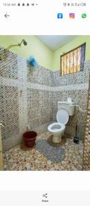 a bathroom with a toilet and a tiled wall at LOFTY DIANI STUDIO'S in Kwale