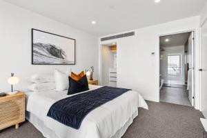 a white bedroom with a large bed with pillows at Hobart CBD Roof Top Penthouse in Hobart