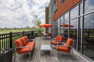 eine Terrasse mit orangefarbenen Stühlen, Tischen und Fenstern in der Unterkunft Holiday Inn Express & Suites - Welland in Welland