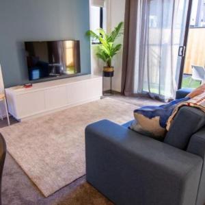 uma sala de estar com um sofá azul e uma televisão em Luxurious inner city 2 bed pad em Christchurch