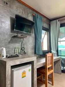 a kitchen with a counter with a tv on the wall at Rinna Resort in Koh Mook