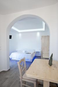 Villa Varnali Small Boutique في مدينة ميكونوس: غرفة بيضاء بسرير وطاولة وكرسي