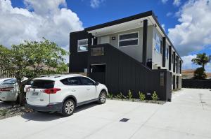 ein weißes Auto, das vor einem Haus parkt in der Unterkunft Redwood Apartments in Rotorua