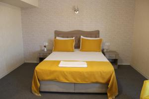 a bedroom with a large bed with yellow sheets and pillows at ANGRAND HOTEL in Ankara