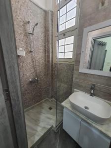 uma casa de banho com uma cabina de duche em vidro e um lavatório. em زافيرو اتينيوس em Alexandria