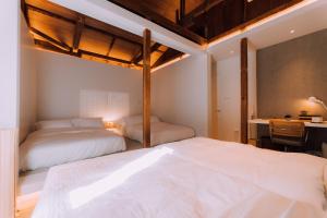 two beds in a room with a desk and a bed at One Harajuku: Private Oasis in Tokyo