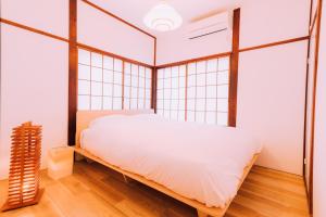 a bedroom with a large white bed and large windows at One Harajuku: Private Oasis in Tokyo
