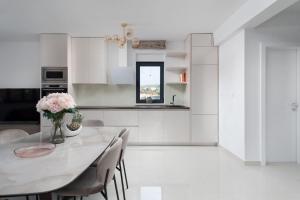 a white kitchen with a white table and chairs at NEW ! Villa Palm Bay 1 & 2 with two heated pool - near sea in Ražanj