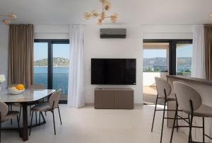 a living room with a television and a table and chairs at NEW ! Villa Palm Bay 1 & 2 with two heated pool - near sea in Ražanj
