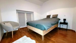 ein Schlafzimmer mit einem Bett und einem Stuhl darin in der Unterkunft L'inattendue - Maison centre ville - Dourdan in Dourdan