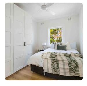 a white bedroom with a bed and a window at Little Manly Getaway in Sydney