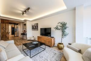 a living room with white furniture and a flat screen tv at Luxury Plaza De Castilla in Madrid