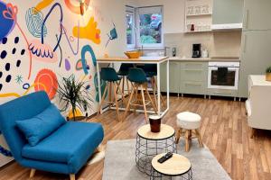 ein Wohnzimmer mit einem blauen Sofa und einer Küche in der Unterkunft Le studio Héloïse - BeCosy rentals - 2 ad + 1 enf in Péruwelz