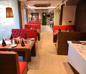 uma sala de jantar com cadeiras vermelhas e mesas num restaurante em Hotel Silver Land New Digha em Digha
