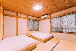 two beds in a room with two windows at Yuzawa Onsen Lodge 1min to LIFT A House in Seki