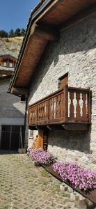 un balcon en bois sur un immeuble avec des fleurs dans l'établissement Maison Sarteur Alloggio ad uso turistico -VDA-LA THUILE- 0065, à La Thuile