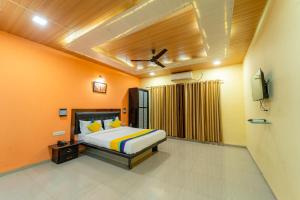 a bedroom with a bed with orange walls and a tv at Itsy By Treebo- Sun N Shade in Matheran