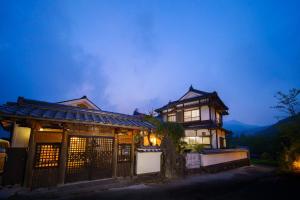 una casa asiática de noche con montañas en el fondo en Yufuin Kurokiya - Vacation STAY 85694, en Yufu