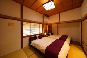 1 Schlafzimmer mit 2 Betten und einem Fenster in der Unterkunft Yufuin Kurokiya - Vacation STAY 85694 in Yufu