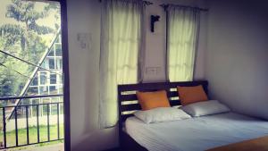 a bedroom with a bed and a window with a balcony at Riverston Nature Villa in Rattota