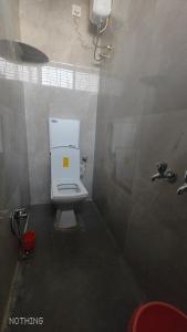 Aadishkti bhakt nivas في Tuljapur: حمام به مرحاض أبيض ومغسلة