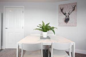 a white dining room table with white chairs and a plant at Two Bed, Two bath, Apartment with Parking Space in Colchester