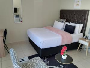 a bedroom with a bed and a table and a chair at EMPEROR LODGE AND TOURS in Germiston