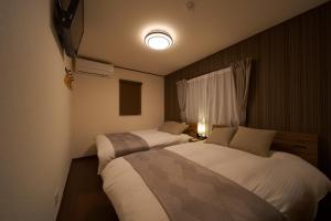 a bedroom with two beds and a light on the wall at Takanoya Hoshi - Vacation STAY 91923 in Yufuin