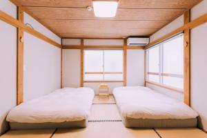 duas camas num quarto com duas janelas em Yuzawa Onsen Lodge 1min to LIFT House em Seki